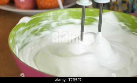Mélangeur de cuisine bat la crème pâtissière crème fouetter tourne rapidement. Robot de cuisine battre les oeufs blancs en blanc une mousse épaisse. Machine en cuisine Banque D'Images