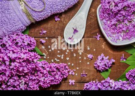 Composition de Spa et de bien-être avec de l'eau fleurs lilas parfumés dans un bol, du sel de mer et de l'absorbant sur fond de bois. L'aromathérapie pour votre détente, vue du dessus Banque D'Images