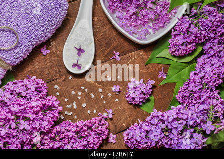 Composition de Spa et de bien-être avec de l'eau fleurs lilas parfumés dans un bol, du sel de mer et de l'absorbant sur fond de bois. L'aromathérapie pour votre détente, vue du dessus Banque D'Images