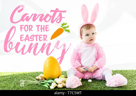 Mignon bébé en costume de lapin assis près de tulipes colorées, les oeufs de poule et œuf d'autruche jaune avec des carottes pour le lapin de Pâques illustration Banque D'Images