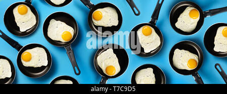 Une cuisine créative avec des œufs frits sur casseroles sur fond bleu. Vue d'en haut. Tendance créative dans un style minimaliste. Mise à plat. Bannière. Banque D'Images