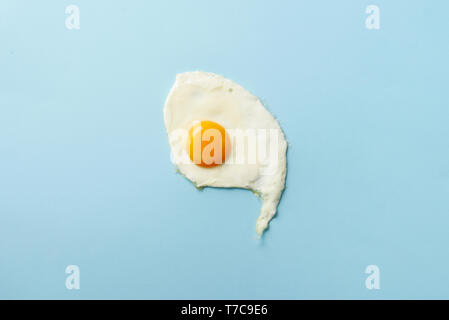 Un œuf frit sur du papier bleu. Cuisine créative concept dans un style minimaliste. Vue d'en haut. Banque D'Images