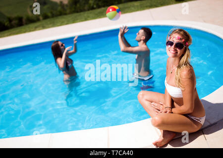 Amis jouant les jeux de ballon dans la piscine Banque D'Images