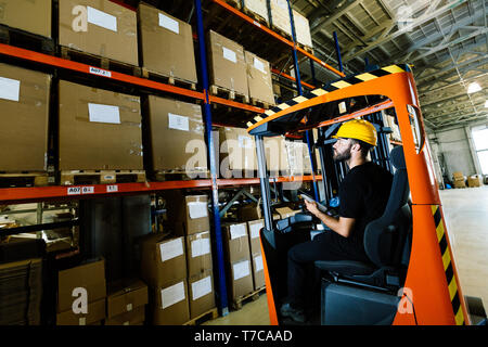 Employé de l'entrepôt logistique faisant travailler avec chargeur chariot élévateur Banque D'Images