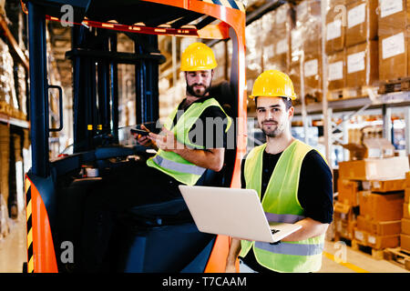 Les employés de l'entrepôt travaillant ensemble avec chargeur chariot élévateur Banque D'Images