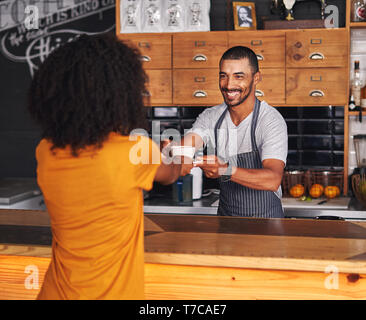 Barista mâle propose un café chaud à la clientèle féminine Banque D'Images