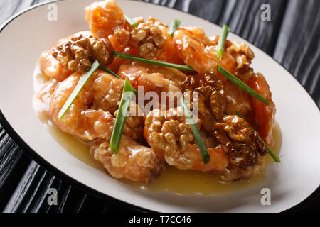 Crevettes au miel sont frits avec une pâte tempura et rapidement sautées dans une sauce au miel et noix sucrées close-up sur une plaque horizontale. Banque D'Images