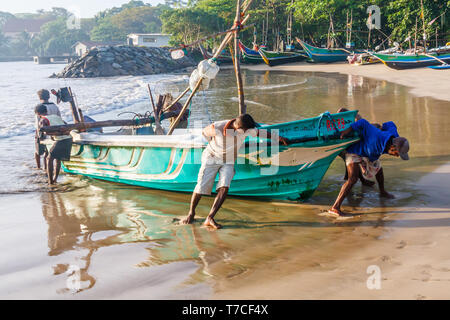 Galle, Sri Lanka - 14 mars 2011 : Les pêcheurs faisant glisser un voile jusqu'à la plage. La plage est également utilisé comme un marché aux poissons. Banque D'Images