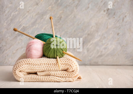 Fil à tricoter avec des aiguilles et un foulard sur la table en bois Banque D'Images