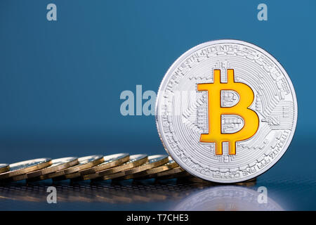 Bitcoin argenté brillant avec logo et symbole de bit de pièces sur fond bleu foncé Banque D'Images