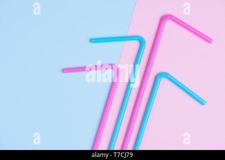 En plastique coloré coocktail potable pailles sur rose et bleu pastel arrière-plan à la mode Banque D'Images