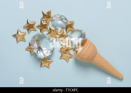 Ice cream wafer cone avec brillant or étoile et gemmes sur fond bleu pastel flatlay Banque D'Images