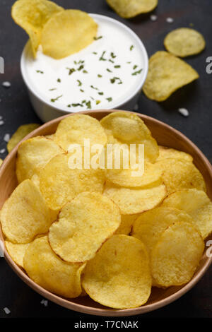 Croustilles de pommes de terre dans un bol avec la sauce trempette sur tableau noir Banque D'Images