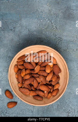 Amandes grillées et salées sur Bol en céramique en vue de dessus de table rustique Banque D'Images