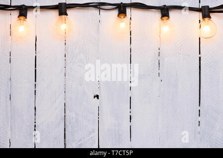 Guirlande de fête sur les lampes en verre blanc en bois peint mur avec copy-space Banque D'Images