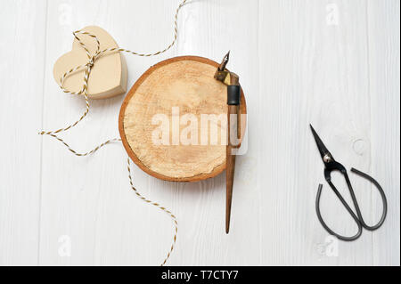 Plume calligraphique, se trouve à proximité d'un cercle en bois avec un papier blanc coeur. carte de souhaits pour la Saint-Valentin avec place pour votre texte. Télévision lay, top vie Banque D'Images