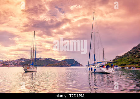 Yachts ancrés sur la mer calme au coucher du soleil dans la baie d'gumsuluk à Bodrum, Mugla, Turquie. Banque D'Images