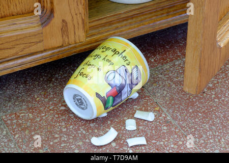 Tasse à café photographes pose sur carrelage avec poignée cassée après une chute d'armoire concept manque de concentration Banque D'Images