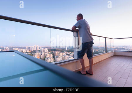 Balcon haut de gamme au centre-ville de la ville moderne. L'homme sur le balcon d'oeil sur la ville en soirée. Banque D'Images