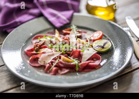 Le carpaccio de boeuf sur plaque avec artichauts tomates séchées et parmesan roquette Banque D'Images