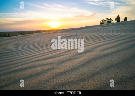Superbe paysage de l'aube deser asiatique sur le sable blanc et de dunes rouges à MUI ne au Vietnam. Coucher de soleil sur l'horizon. Les voyageurs à l'arrière-plan avec Banque D'Images