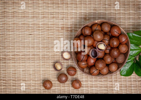 Les noix de macadamia dans le bol sur la paille (bambou) Contexte. Vue de dessus Banque D'Images