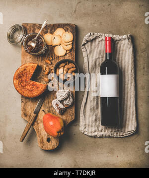 Vin et snack-set. Télévision à jeter de bouteille de vin avec étiquette vierge, vintage tire-bouchons, de fromage et d'apéritifs sur planche de bois sur fond de béton gris, Banque D'Images