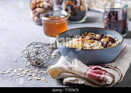 Variété de fruits secs, noix, miel et flocons d'avoine dans un bol et différents pots de verre pour la cuisson des petit-déjeuner sain ou muesli muesli énergie b Banque D'Images