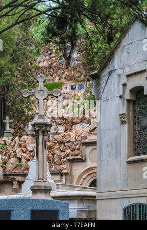 La crypte et la croix libre sur l'arrière-plan de mur de pierre de sépultures sur le cimetière de Montjuic, Barcelone, Catalogne, Espagne Banque D'Images