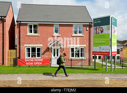 Man Walking cours des maisons dans le Mile, un développement de nouveaux logements par Persimmon Homes, près de Pickering, East Yorkshire, England UK Banque D'Images