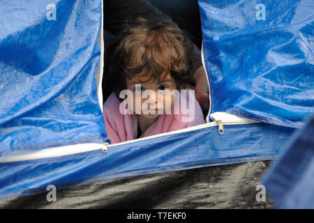 Le Pirée, Grèce. 27 mars 2016. Un enfant se profile à partir d'une tente sur le port du Pirée où plus de 5 000 réfugiés et migrants sont bloqués. Banque D'Images