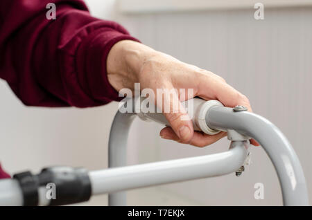 Mains d'une femme senior sur les poignées d'une marchette. Les soins de réadaptation et de concept. Banque D'Images