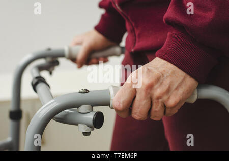 Mains d'une femme senior sur les poignées d'une marchette. Les soins de réadaptation et de concept. Banque D'Images
