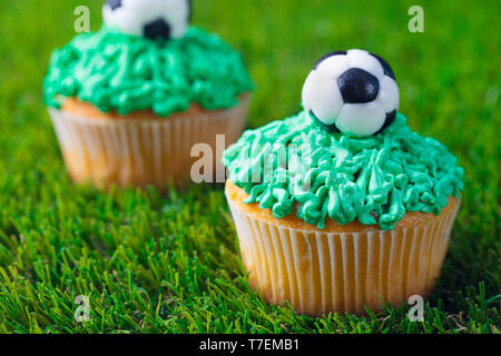 Partie de football, anniversaire cupcake décoré sur fond d'herbe verte. Close up. Banque D'Images