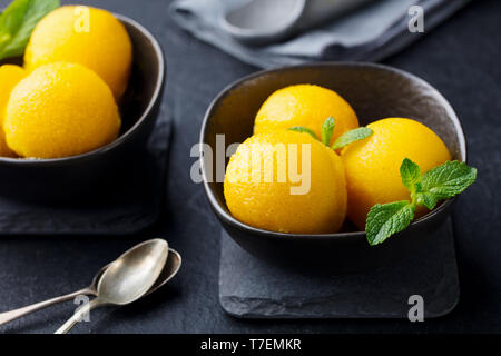 Glace à la mangue, sorbet aux fruits tropicaux en noir sur fond ardoise bol. Close up. Banque D'Images