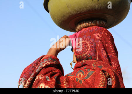 Woman balancing des cow-dung sur la tête à l'exécution pour le séchage et l'a utilisé pour faire du feu Banque D'Images