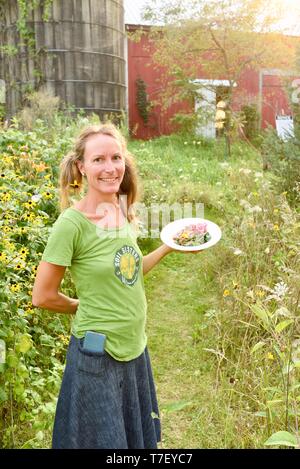 Chef traiteur agricultrice sur sa ferme porcine, avec un repas préparé avec les porcs du patrimoine qu'elle soulève, le dîner à la ferme, de Blanchardville, WI, USA Banque D'Images