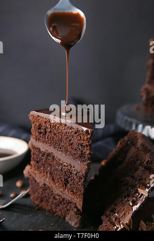 Verser du chocolat sur morceau de gâteau savoureux sur la table Banque D'Images