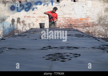 Travailleur masculin est perçu comme il peint cuir avec projection de peinture machine dans la zone de traitement du cuir (tanneries district) à Dhaka, Bangladesh Banque D'Images