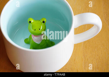 Figurine grenouille mignon dans le mug blanc avec base de Sunny Banque D'Images