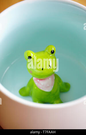 Figurine grenouille mignon dans le mug blanc avec base de Sunny Banque D'Images