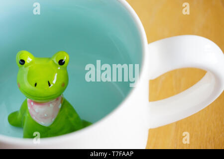 Figurine grenouille mignon dans le mug blanc avec base de Sunny Banque D'Images