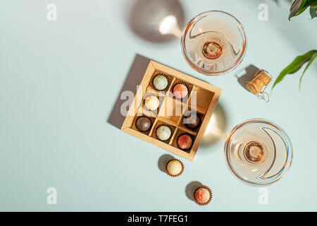 Champagne ou de vin dans l'élégant quartier de verres, une boîte de chocolats sur un fond bleu. Copier l'espace. Mise en page (top view). Télévision Banque D'Images