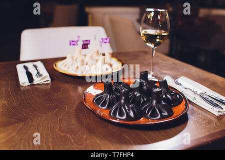 La cuisine arménienne et géorgienne traditionnelle. Tendance, noir géorgien khinkali suluguni avec de la viande et du fromage, sur une table en bois dans un restaurant. Vin sur Banque D'Images