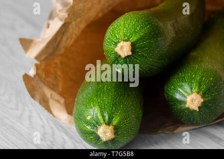 Courgette biologique dans un sac en papier sur bois gris. Recycler les emballages concept. Pas de déchets plastiques. Banque D'Images