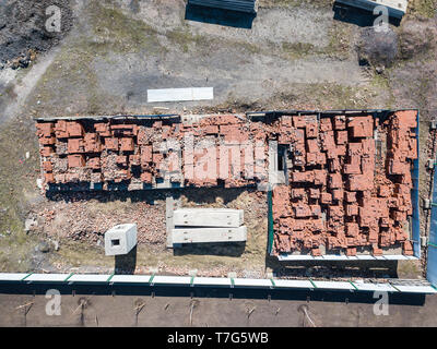 Un grand nombre de briques rouges empilés sur des palettes près du site de construction en plein air, entourée d'une clôture, sur une journée ensoleillée. Building Banque D'Images