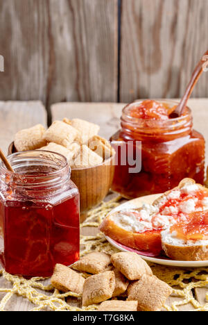 Un petit-déjeuner maison naturelle table avec des toasts avec caillé et fraise sucrée et apple des confitures et des en-cas sur blé carré tricoté jaune serviette sur rustic Banque D'Images