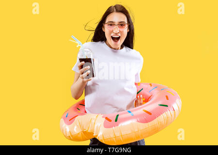 Belle femelle portrait en pied isolé sur fond jaune studio. Young smiling woman in red lunettes de soleil avec un verre. Expression du visage, l'été, week-end, resort concept. Couleurs tendance. Banque D'Images