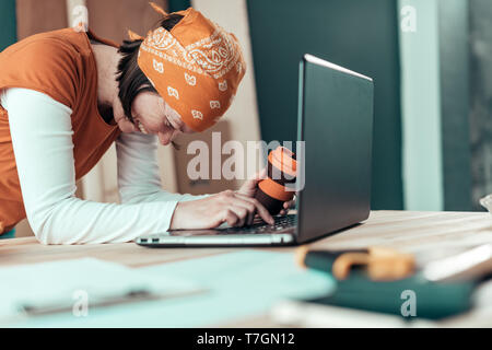 Happy smiling female carpenter lors de chat en ligne avec le client sur un ordinateur portable dans l'atelier de menuiserie Banque D'Images