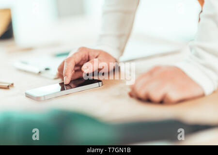 Female carpenter est l'utilisation de téléphone mobile pour la messagerie texte, la saisie de sms sur l'écran tactile du smartphone, selective focus Banque D'Images